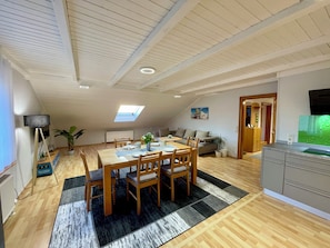 A spacious living area with a dining table, chairs, a sofa, a kitchen area, and a skylight. - Gemütliche Ferienwohnung Taube am Fuße des Stammbergs in der Fränkischen Toskana (Schammelsdorf)