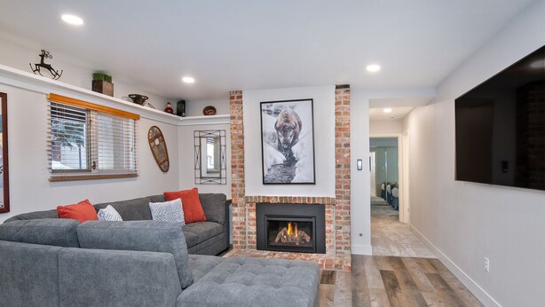 A modern living room with a grey sectional sofa, a fireplace, and a large TV mounted on the wall.