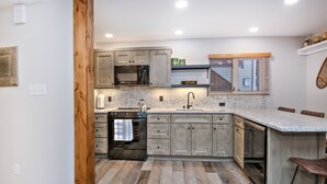 A kitchen with wooden cabinets, a stainless steel microwave, a built-in oven, and a granite countertop.