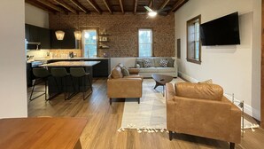 Una cocina moderna con una isla central, un comedor con mesa de madera y una sala de estar con sofá y mesa de centro.