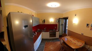 Cozinha compacta com geladeira, pia e área de refeições.