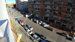 Edifício residencial com várias andares, varandas, vista para a rua e carros estacionados.