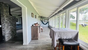 Ein langer, schmaler Raum mit Holzboden, einem Tisch mit Tischdecke und einer Hängematte.