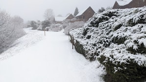 A snow-covered pathway leading to a row of houses with sloped roofs. - Duplex 4/6 Pers Dans une Ambiance Chaleureuse Avec vue Imprenable sur le Sancy (Murat-le-Quaire)
