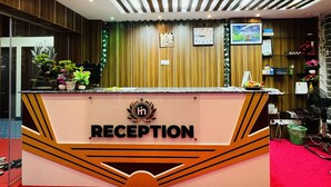 A reception desk with a clock, plants, and a framed picture on the wall.
