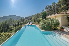 Relax by the serene pool surrounded by lush greenery and rolling hills.