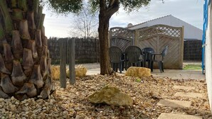 Een tuin met een houten omheining, een pergola en buitenmeubels.