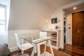 A room with a glass-top table, white chairs, a white bench, a wooden door, and a white wall with a framed picture. - Cosy Studio Apartment - Embrace Edinburgh's Charm - Pass the Keys (Edinburgh)