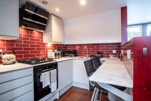 A modern kitchen with a red brick backsplash, white cabinetry, and a built-in island with bar stools.
