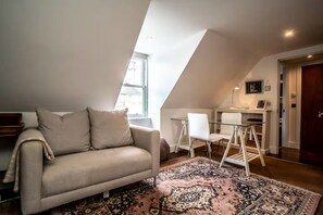 A loft-style room with a sofa, a dining area with chairs, a rug, and a television.