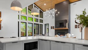 A modern kitchen with a large island, pendant lights, and a fireplace.