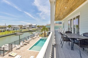 A poolside area with lounge chairs, a pool, and a view of a marina.