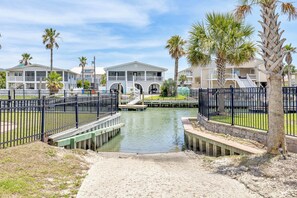 A gated marina with a dock, palm trees, and a building with balconies.
