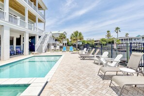 A pool area with lounge chairs and a building with multiple balconies.