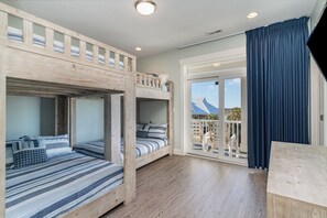 A room with bunk beds, a wooden desk, and a balcony with a view.