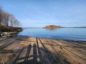 Ein Strand mit blauem Himmel, ruhigem Wasser und einer entfernten Insel.