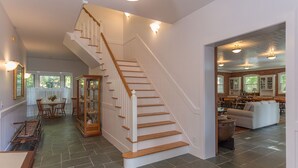 Ein geräumiger Wohnbereich mit Treppe, einem Essbereich und einer durch einen offenen Durchgang sichtbaren Küche.