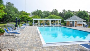 Ein rechteckiger Pool mit gefliestem Sonnendeck, umgeben von Liegestühlen und Sonnenschirmen.