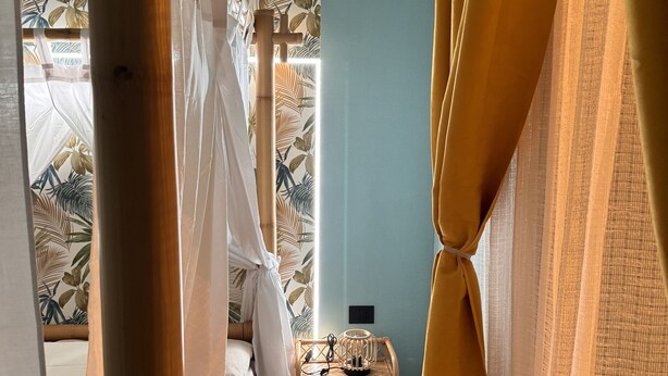 A bedroom with a bed, a nightstand, and a window with curtains.