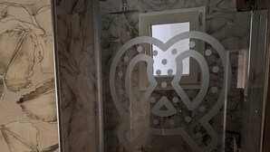 A shower with a floral wallpaper design and a heart-shaped window.