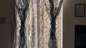 A room with a large window covered by patterned curtains.
