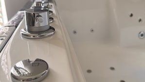 A white bathtub with a faucet and control knobs.