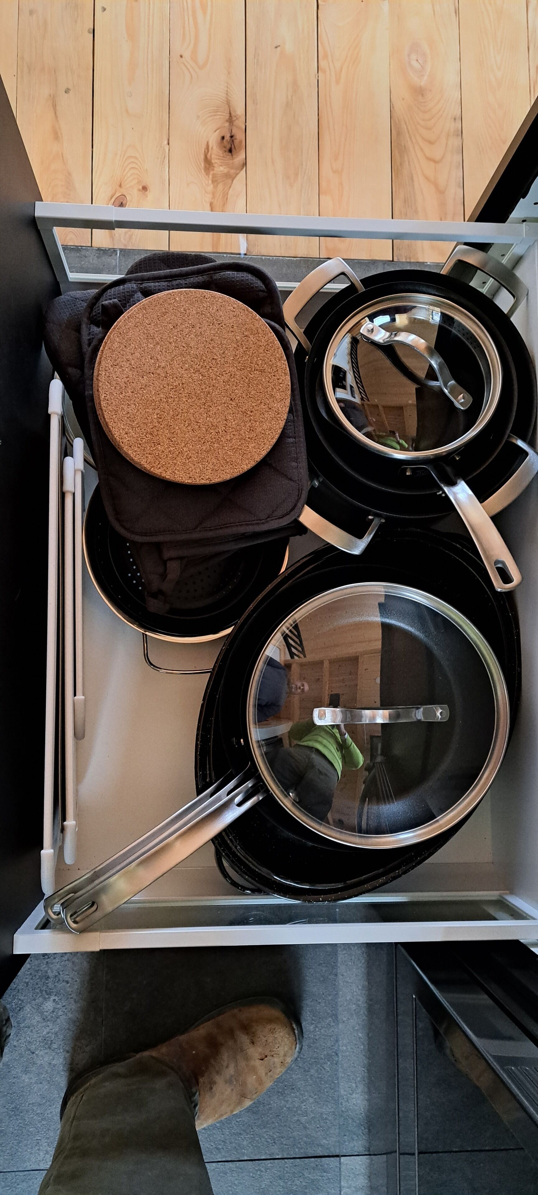 A kitchen with a wooden floor, a black pot with a cork lid, and a stainless steel pan with a lid.