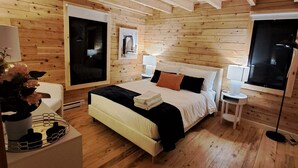Un dormitorio con paneles de madera, una cama, mesitas de noche y una ventana.