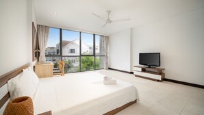 Habitación de hotel moderna con una cama grande, un televisor y vistas a la ciudad a través de amplias ventanas.