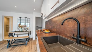 Een moderne keuken met een inbouwspoelbak, houten bankzit en een rustieke achterwand.