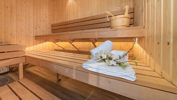 Een houten sauna met banken, inclusief een bank met handdoeken en bloemen.