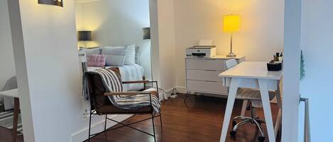 A modern bedroom with a bed, bedside table, and a desk with a lamp.