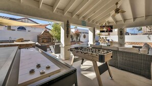 Eine Terrasse im Freien mit einer Tischfußballmaschine, einer Sitzgelegenheit und einem Kamin aus Stein.