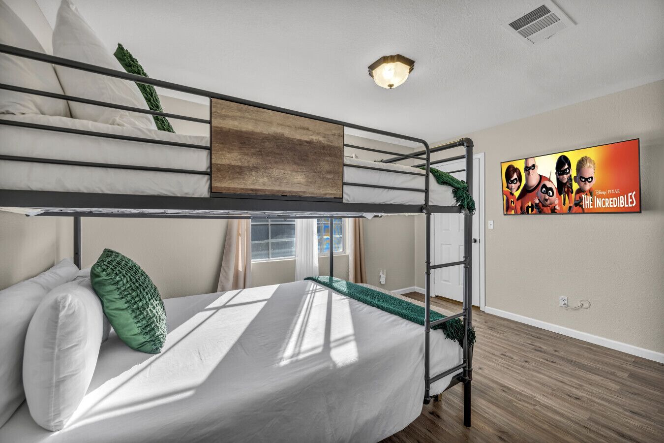 Ein Schlafraum mit Etagenbetten und einem Poster von 'The Incredibles' an der Wand.