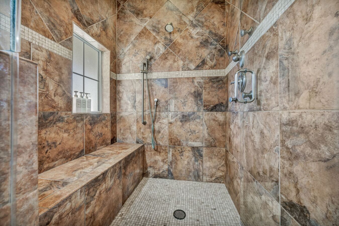 A walk-in shower with a bench, tiled walls, and a showerhead.