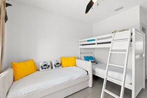 A room with a white sofa, a bunk bed, and a ladder.