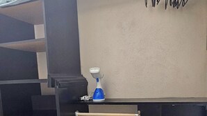 Una habitación con una cama, un escritorio y una silla. Hay una estantería con varios objetos.