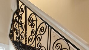 A staircase with a decorative metal railing and a carpeted landing. - London Luxury House Sleeps 16 , Close to Tube, Free Parking, Garden,  Free Wifi (Ilford)