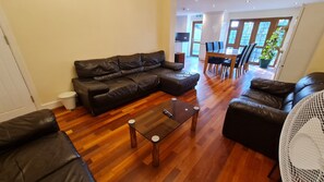 Una sala de estar con un sofá modular, una mesa de centro de vidrio y un comedor con una mesa y sillas.