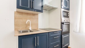 Una cocina compacta con lavamanos, estufa, horno y microondas.