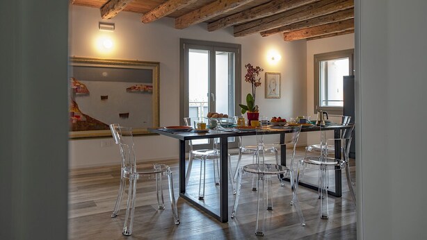 Un comedor con techo de madera, un espejo grande y sillas transparentes.