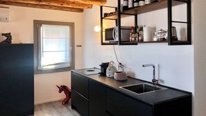 Una cocina moderna con armarios oscuros, techo de madera, estante empotrado para vinos y un microondas.