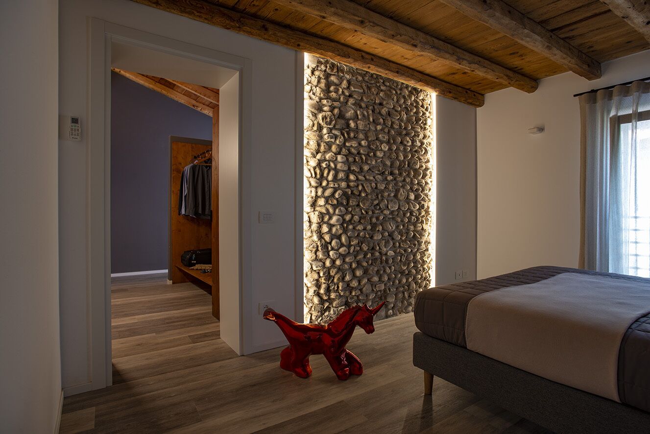 Une chambre avec un mur en pierre, un plancher en bois et un lit.