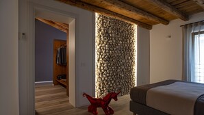 Un dormitorio con pared de piedra, suelo de madera y una cama.
