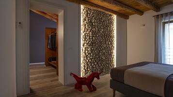 Une chambre avec un mur en pierre, un plancher en bois et un lit.
