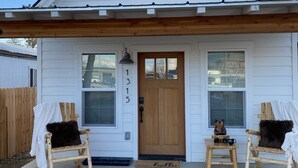A white house with a gabled roof, a front door, and two rocking chairs on the porch. - The Comfy Bear Cottage! Beautiful 2 bed/1bath home minutes from skiing and lake. (Sandpoint)