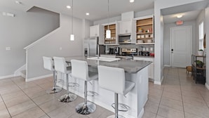 A modern kitchen with a central island, bar stools, and built-in appliances.