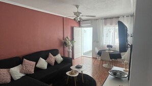 Una sala de estar con un sofá negro, una pequeña mesa de centro y un comedor con mesa y sillas.