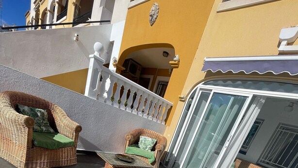 Un patio con mobiliario de mimbre y una puerta de cristal.