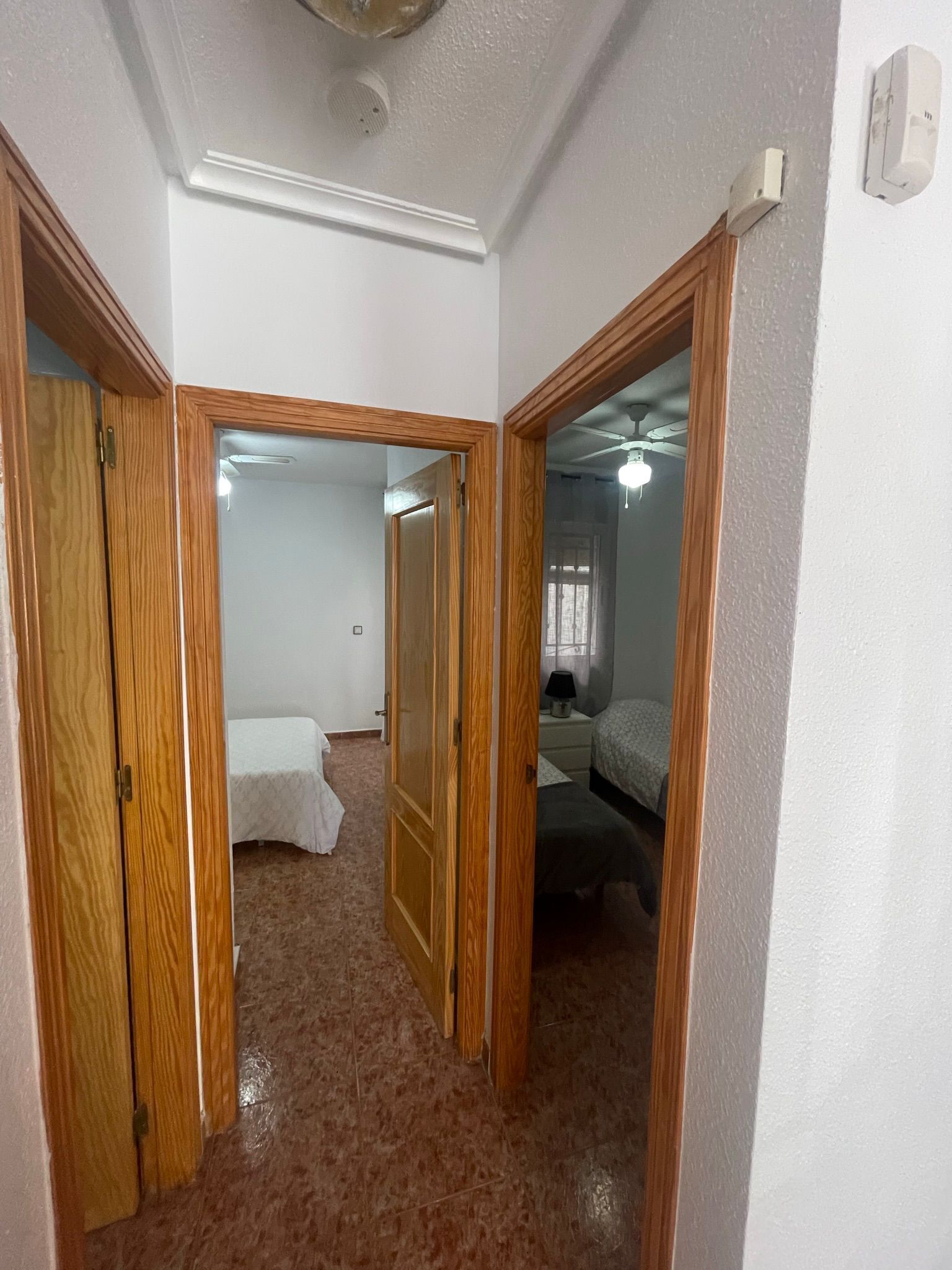 A hallway with wooden doors leading to a bedroom and a bathroom.
